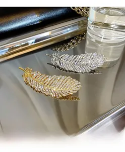 Detailed close-up of sparkling rhinestone feather hair clips in gold and silver finish