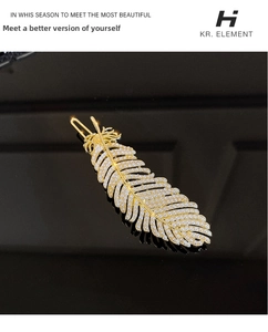 Close-up of golden feather hair clip with pearl detailing on a black background