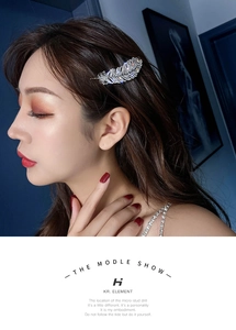 Close-up of elegant silver feather rhinestone hair clip worn by a model in a side view