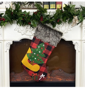 Classic red and black plaid Christmas stocking with grey faux fur cuff hanging on fireplace