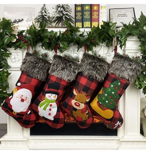 Close-up of four plaid Christmas stockings with plush trim hanging on a white fireplace