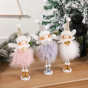 Three plush Christmas angel dolls with feathers and sequins displayed on a festive table