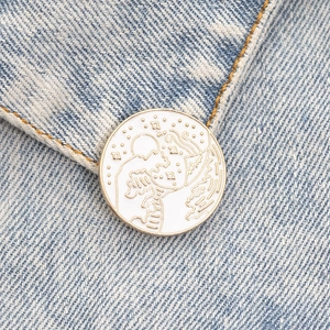 Macro shot of circular enamel brooch with sun and mountains on blue denim fabric