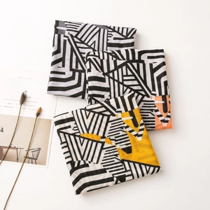 Detail of printed summer scarves featuring black and white geometric patterns and vibrant accents