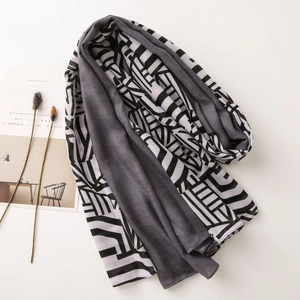 Detail view of lightweight gray scarf with black and white geometric pattern on white surface