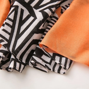 Close-up of lightweight orange and geometric print scarf fabric with fine stitching