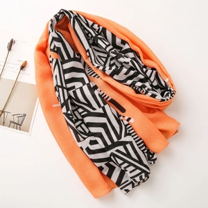 Detail of bright orange and geometric patterned lightweight summer shawl on white background