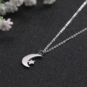 Macro detail of polished stainless steel crescent moon and star pendant necklace