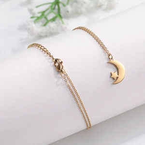 Detail shot of a gold-tone crescent moon and star pendant on a fine link chain necklace