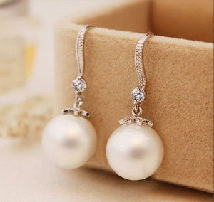Elegant S-curve pearl earrings with cubic zirconia inlay on velvet jewelry box