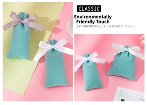 Detail of mint green velvet jewelry drawstring pouch with satin bow on marble tray