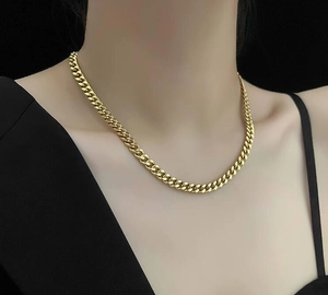 Close-up of a wide chunky gold chain necklace worn on neck with modern industrial style
