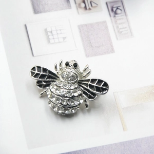 Detail view of a bee brooch featuring sparkling rhinestones and black enamel wings