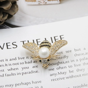 Elegant bee brooch with diamond-set wings and a large pearl on a gold-tone base