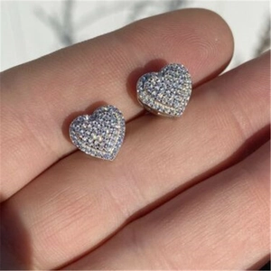 Detailed close-up of heart-shaped earrings with micro-set zircons held by hand