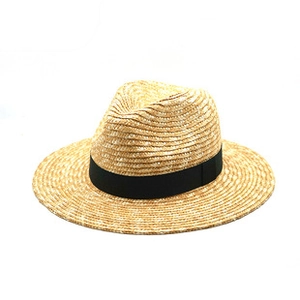 Détail d'un chapeau de paille tressé avec ruban noir contrasté en couleur beige naturel