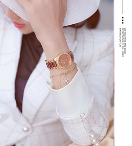 Detail of luxury ceramic brown quartz watch and daisy bracelet set on female wrist