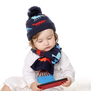Détail d'un ensemble bonnet et écharpe en tricot bleu marine avec motifs dinosaures