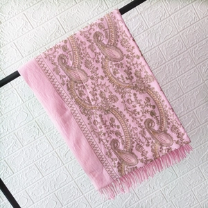 Close-up of pink cashmere shawl featuring golden paisley embroidery and elegant fringe details