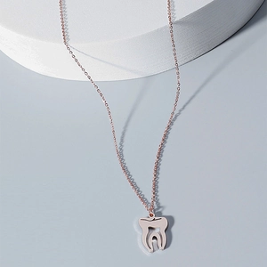 Détail du pendentif dent en or rose poli sur une fine chaîne à maillons minimaliste