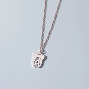 Gros plan détaillé d'un collier avec pendentif dent or rose au design ajouré épuré