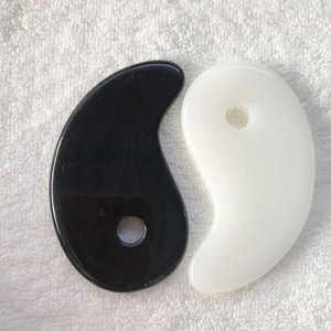 Heart-shaped resin gua sha tools in black and white colors on a white towel background