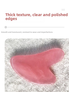 Detailed view of heart-shaped pink resin gua sha tool with marble texture on soft white fabric