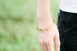 Close-up of a double-layer gold beaded bracelet worn on a wrist in an outdoor setting