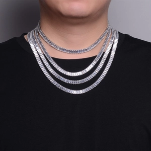 Detailed close-up of layered silver tennis necklaces with rectangular cut gemstones on a model