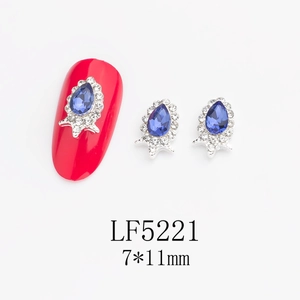 Detailed view of teardrop blue nail crystal with silver base and tiny white rhinestones