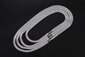 Detail shot of three silver iced-out Cuban link necklaces with square zircon stones and fold-over clasps