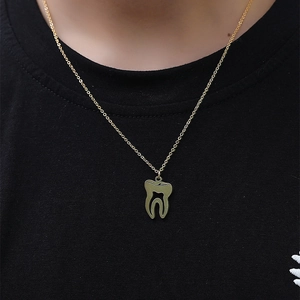 Détail d'un pendentif en forme de dent dorée sur une chaîne fine portée par un mannequin