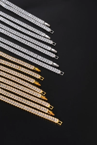 Macro view of gold and silver hip hop cuban link bracelets with square-cut clear crystals