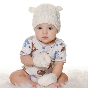 Close-up of baby knitted beanie with cute ears and matching gloves in soft cream white