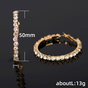 Exaggerated large gold round hoop earrings with white zircons on a black background
