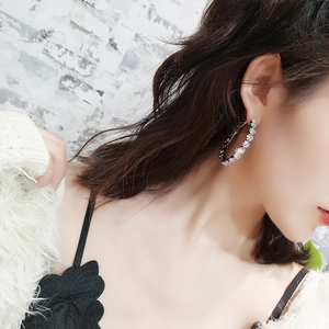 Detail view of oversized silver hoop earrings with shimmering crystal embellishments