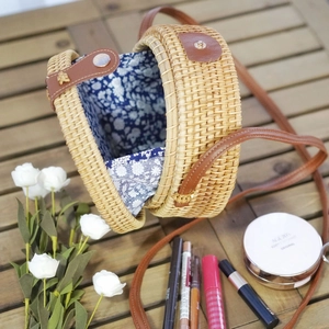 Detail of round handmade rattan bag with floral lining and brown leather closure