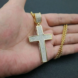 Iced-out gold plated cross pendant necklace with sparkling stones on a curb chain