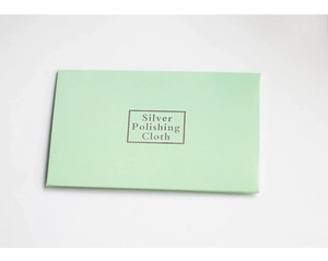 Detail view of light green jewelry gift box containing a specialized silver polishing cloth