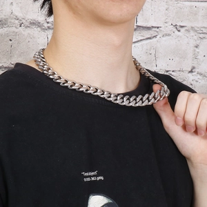 Silver Cuban link chain necklace for men shown on a model against a textured wall