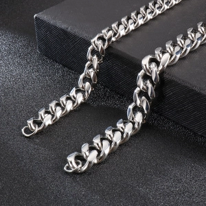 Close-up of polished silver Cuban link chain necklace on a textured black gift box