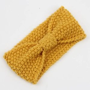 Detail of ginger yellow corn grain knitted headband with central bow design texture