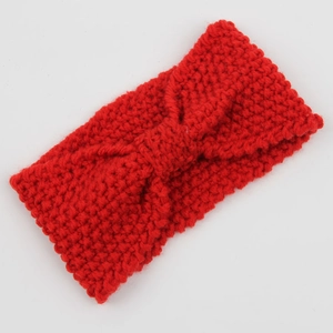 Close-up of red chunky knit headband with twisted knot design in soft wool texture