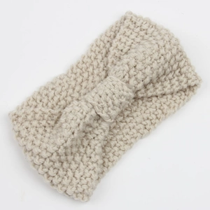 Detailed close-up of beige chunky knit headband with bow design on white background