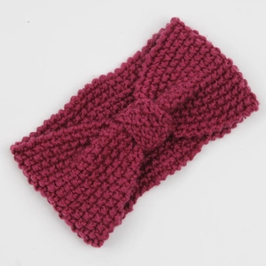 Close-up of berry red chunky knit headband featuring a textured bow design for winter