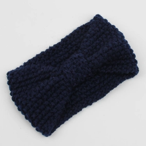 Detail of navy blue knitted headband featuring chunky corn kernel texture and bow design