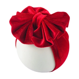 Detail of red oversized velvet bow headband for infants with plush texture and elastic band