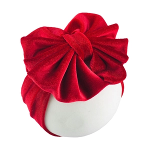Detailed close-up of a vibrant red velvet baby headband with a large velvet bow