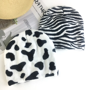 Winter knitted beanies featuring black and white zebra and cow patterns in a flat lay view