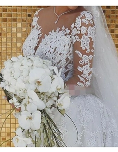 Détail des manches en dentelle florale et broderies de paillettes sur la robe de mariée